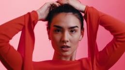 Still photo of woman dressed in red, staring intently at camera