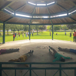 Four performers lay in a semi circle, under a gazebo at Mushtari Afroz’s Choreo-xperience Public Spaces, 2023.