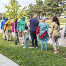 A group of performers and spectators line up alongside a sidewalk and participate in the performance during Mushtari Afroz’s Choreo-xperience Public Spaces, 2023.