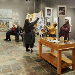 Listeners sit and stand watching Chelsea Smith’s Artist Talk at the Temiskaming Art Gallery, 2023.