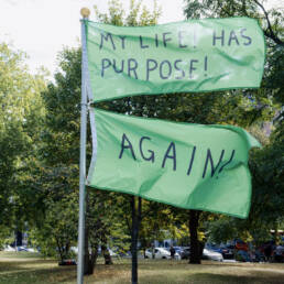 Owen Marshall’s flag installation; two green flags, top: “MY LIFE! HAS PURPOSE!” and bottom: “AGAIN!”, 2023.