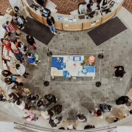 An aerial image of people attending Myung-Sun Kim’s exhibition Rituals for Belonging at Toronto Public Library – Lillian H. Smith Branch, in the centre of the roomher exhibition display laid out, 2023.
