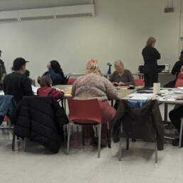 A group of people sit around a table while working at Owen Marshall's Artist Talk & Workshop at the Toronto Public Library, Parkdale Branch, 2023.